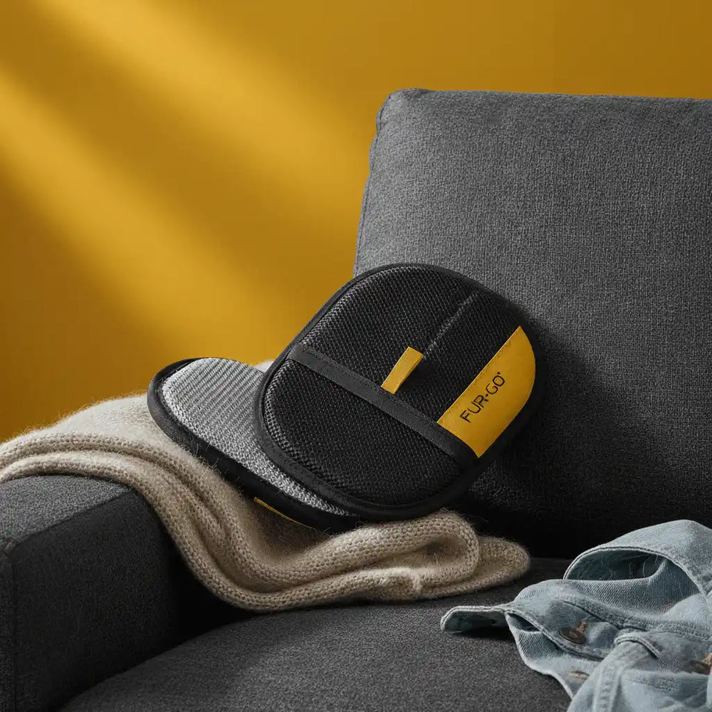 A completely clean dark grey sofa with the yellow and black Fur-Go pet hair remover glove resting on the cushion after removing all fur